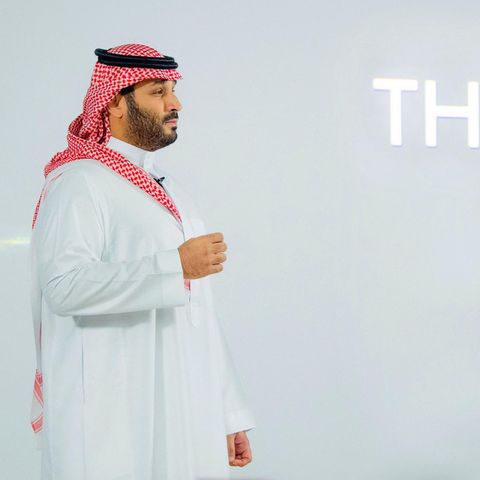 Der Kronprinz Saudi-Arabiens, Mohammed bin Salman, steht im Profil vor einer weißen Wand mit dem Schriftzug "The Line"