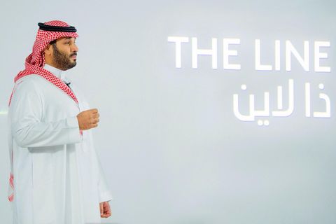 Der Kronprinz Saudi-Arabiens, Mohammed bin Salman, steht im Profil vor einer weißen Wand mit dem Schriftzug "The Line"
