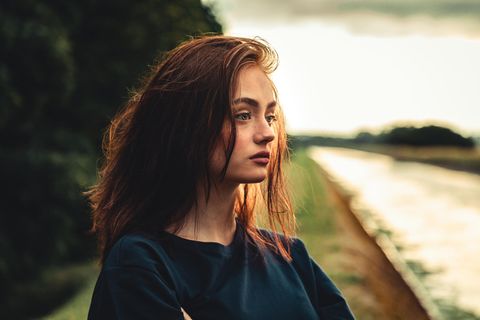 Eine Frau schaut mit leerem Blick auf einen Fluss.