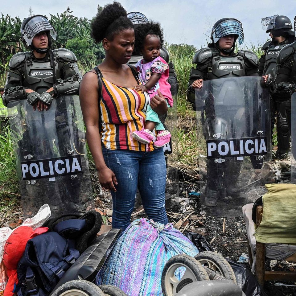 Cali, Kolumbien. Von Polizisten umringt begutachtet eine Frau mit Kind auf dem Arm ihre Habseligkeiten. In Cali hat die Bereitschaftspolizei ein Grundstück geräumt, das zuletzt rund 1500 Familien besetzt hatten.