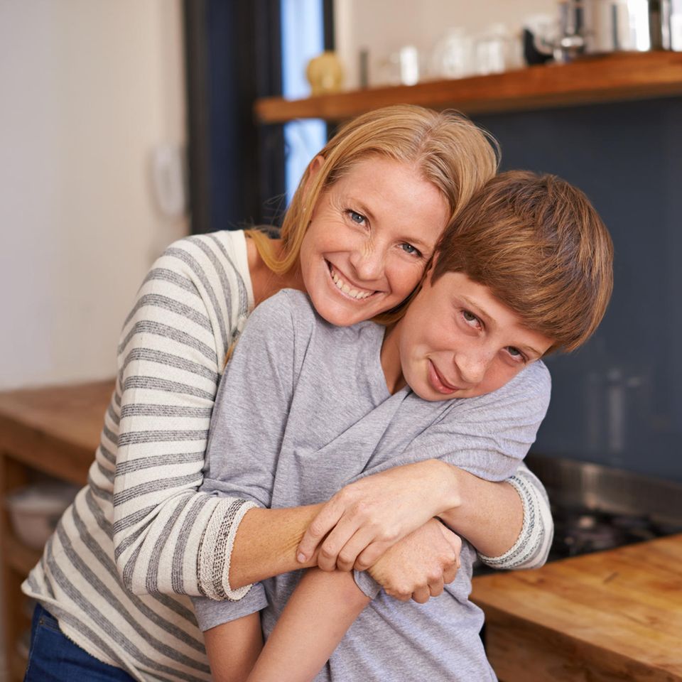 Eine Mutter umarmt ihren verschämten Teenager-Sohn