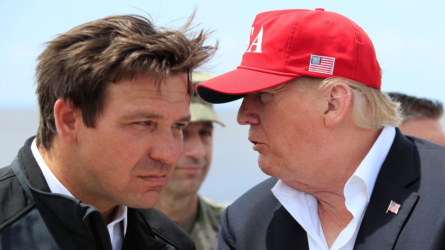 Ron DeSantis hört angestrengt zu, was Donald Trump ihm ins Ohr sagt