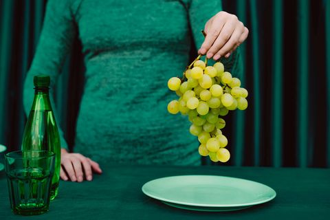 Eine Frau in grün hält einen Strang Weintrauben