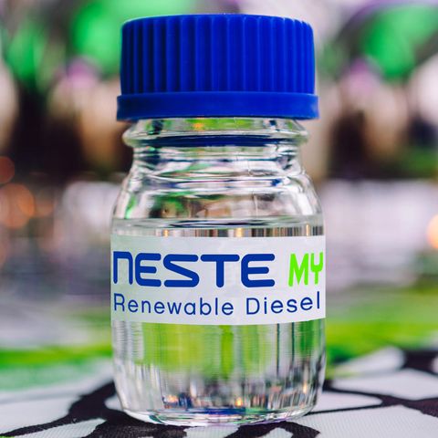 Im Bildvordergrund ist eine Flasche mit einer durchsichtigen Flüssigkeit und der Aufschrift "Neste MY Renewable Diesel" zu sehen
