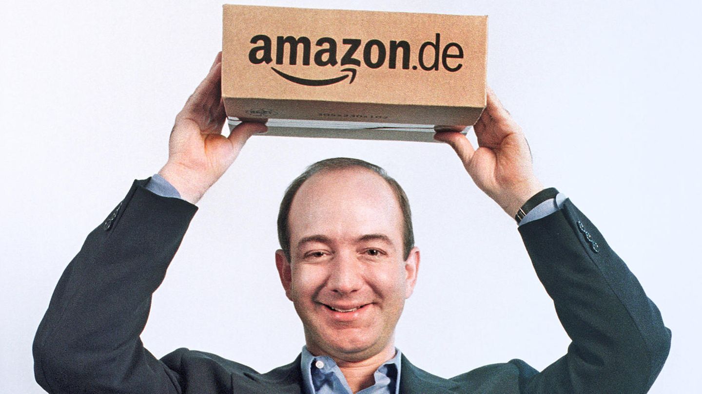 Amazon-Chef Jeff Bezos hält einen Karton über seinem Kopf