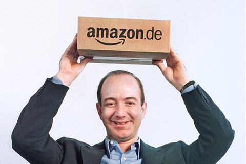 Amazon-Chef Jeff Bezos hält einen Karton über seinem Kopf