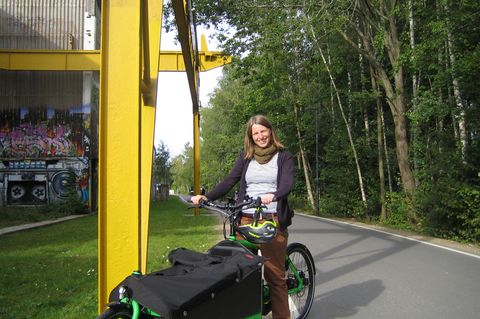 Junge Frau auf grünen Lastenrad