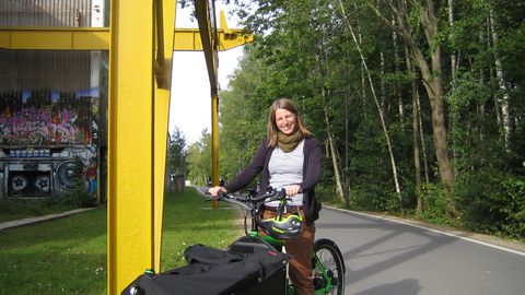 Junge Frau auf grünen Lastenrad
