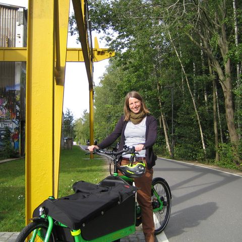 Junge Frau auf grünen Lastenrad