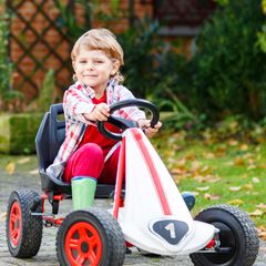 Ein kleiner Junge sitzt auf einem Kettcar