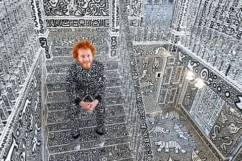 Sam Cox ist auf einer Treppe in seinem vollgekritzelten Haus