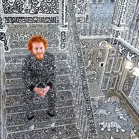 Sam Cox ist auf einer Treppe in seinem vollgekritzelten Haus