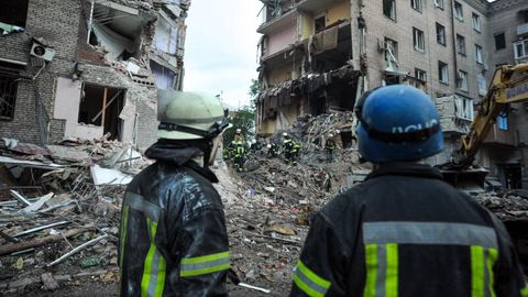 Rettungskräfte schauen auf die Trümmer eines zerstörten Wohnhauses.
