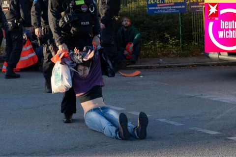 Eine Klimaaktivistin der "Letzte Generation" wird von einem Polizisten von der Autobahnabfahrt in Berlin gezogen