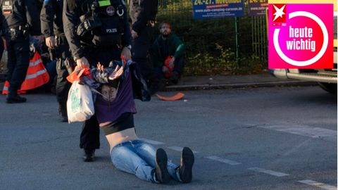 Eine Klimaaktivistin der "Letzte Generation" wird von einem Polizisten von der Autobahnabfahrt in Berlin gezogen