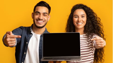 Prime Day Laptop-Deals: Ein Mann und eine Frau halten einen Laptop in der Hand, grinsen und zeigen auf das Modell.