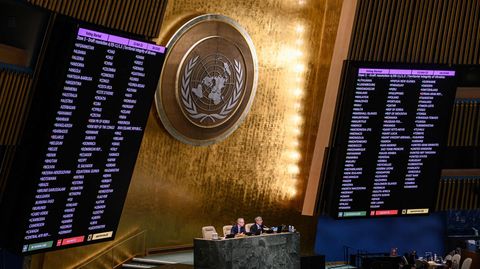 Neben einer goldenen Wand mit UN-Wappen zeigen große Monitore das Abstimmungsergebnis
