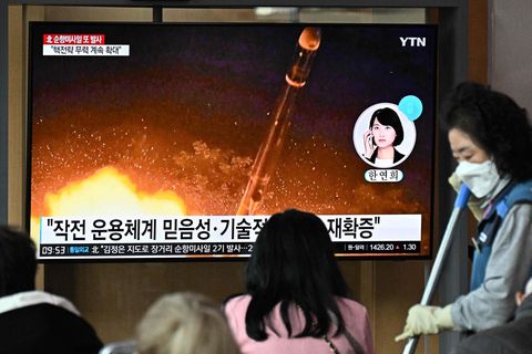 Ein schwarzhaariges Mädchen sitzt vor einem Fernseher, auf dem eine Rakete startet. Auf dem Bildschirm sind koreanische Zeichen