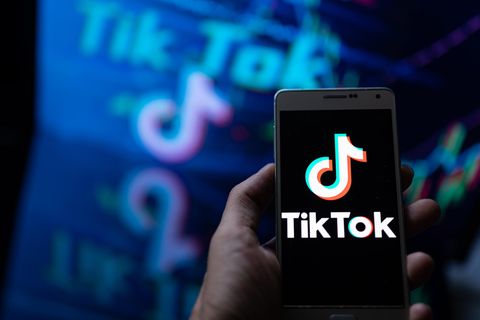 Eine Hand hält ein Smartphone in der Hand, auf dem Bildschirm ist das Logo von TikTok