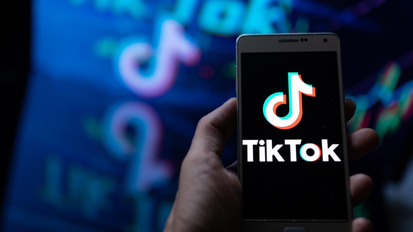 Eine Hand hält ein Smartphone in der Hand, auf dem Bildschirm ist das Logo von TikTok