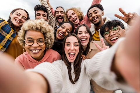 Eine Frau lacht mit vielen Freundin auf einem Selfie.