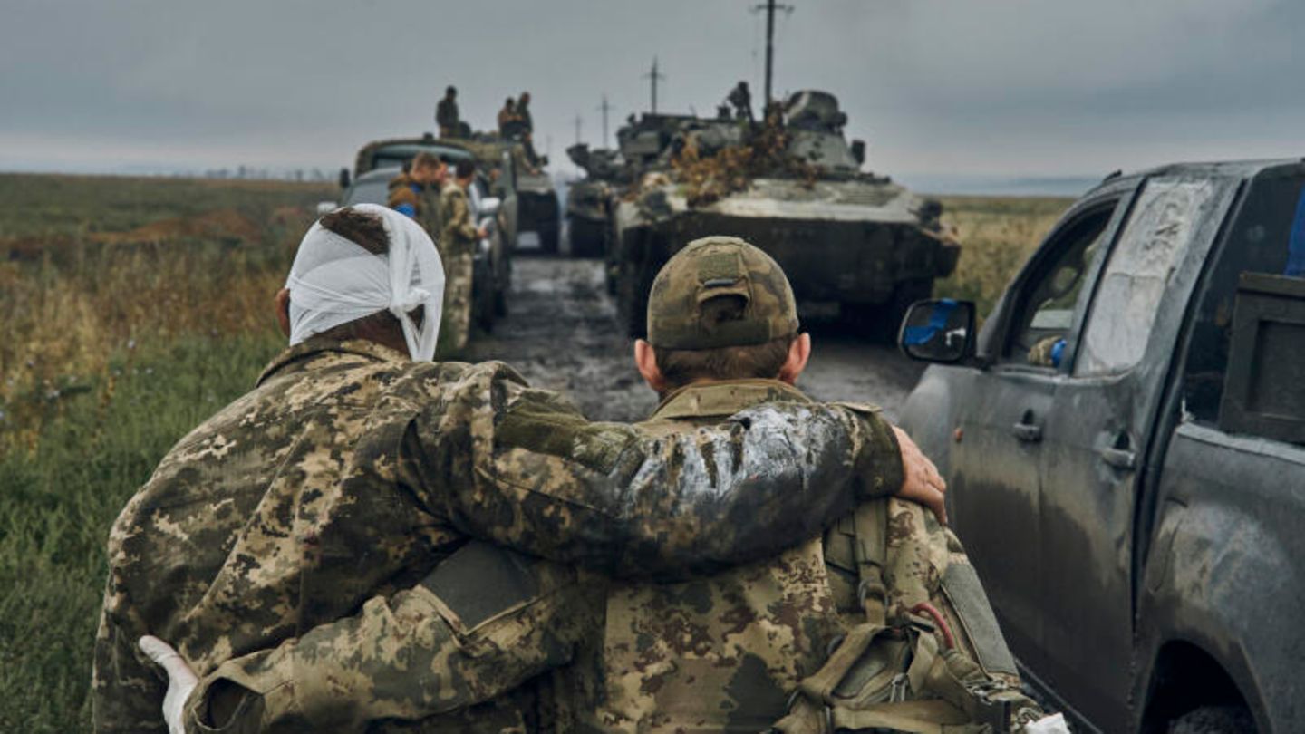 Ein ukrainischer Soldat hilft einem verwundeten Kameraden im befreiten Gebiet in der Region Charkiw