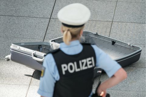 Eine Polizistin steht vor einem leeren Koffer.