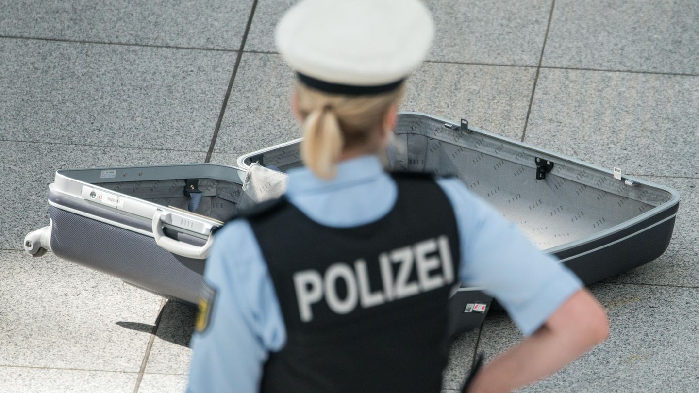 Eine Polizistin steht vor einem leeren Koffer.