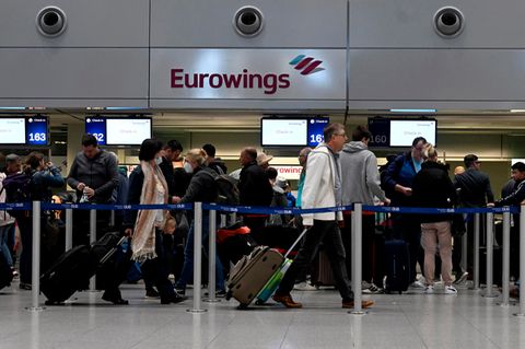 Nordrhein-Westfalen, Düsseldorf: Reisende stehen am Eurowings-Check-in-Schalter Schlange