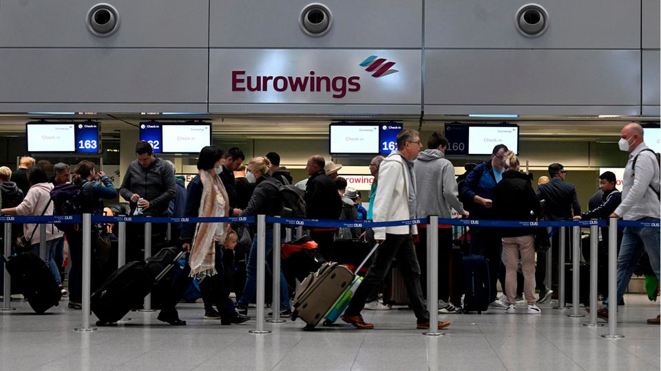 Nordrhein-Westfalen, Düsseldorf: Reisende stehen am Eurowings-Check-in-Schalter Schlange