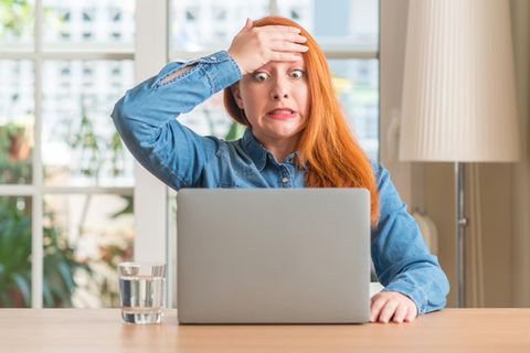 Eine verzweifelte Frau vor dem Laptop