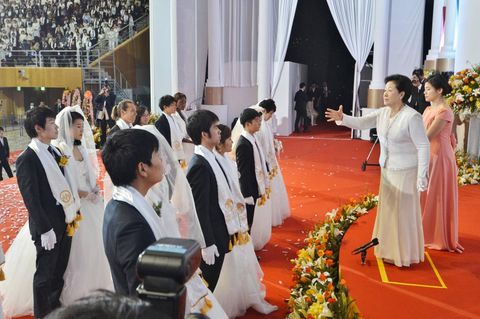 Eine Frau segnet mehrere Paare bei einer Massentrauung der Vereinigungskirche in Südkorea