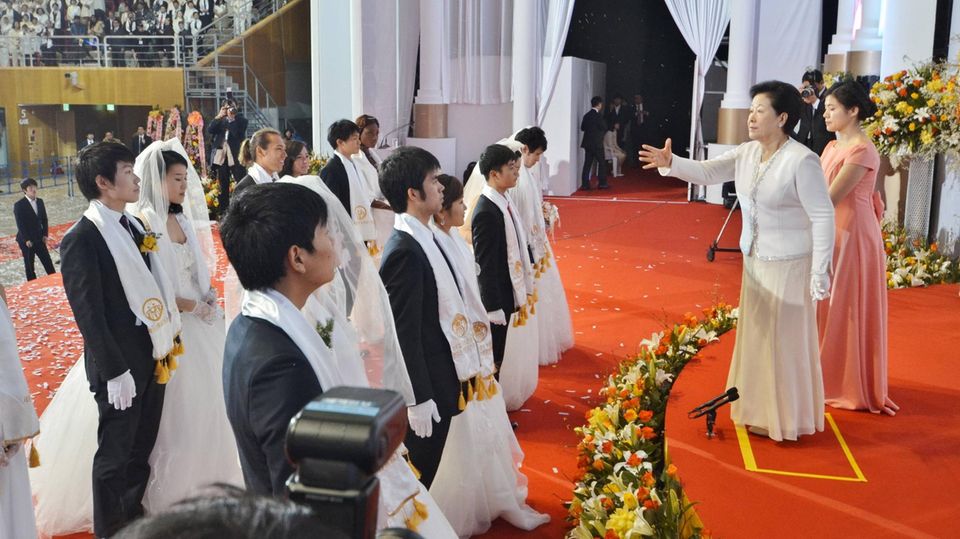 Eine Frau segnet mehrere Paare bei einer Massentrauung der Vereinigungskirche in Südkorea