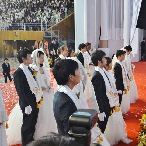 Eine Frau segnet mehrere Paare bei einer Massentrauung der Vereinigungskirche in Südkorea