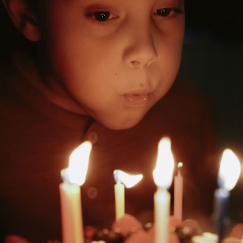Eine Junge pustet Geburtstagskerzen aus