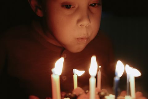 Eine Junge pustet Geburtstagskerzen aus