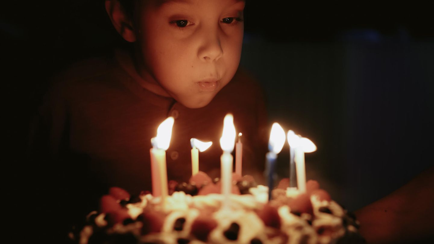 Eine Junge pustet Geburtstagskerzen aus