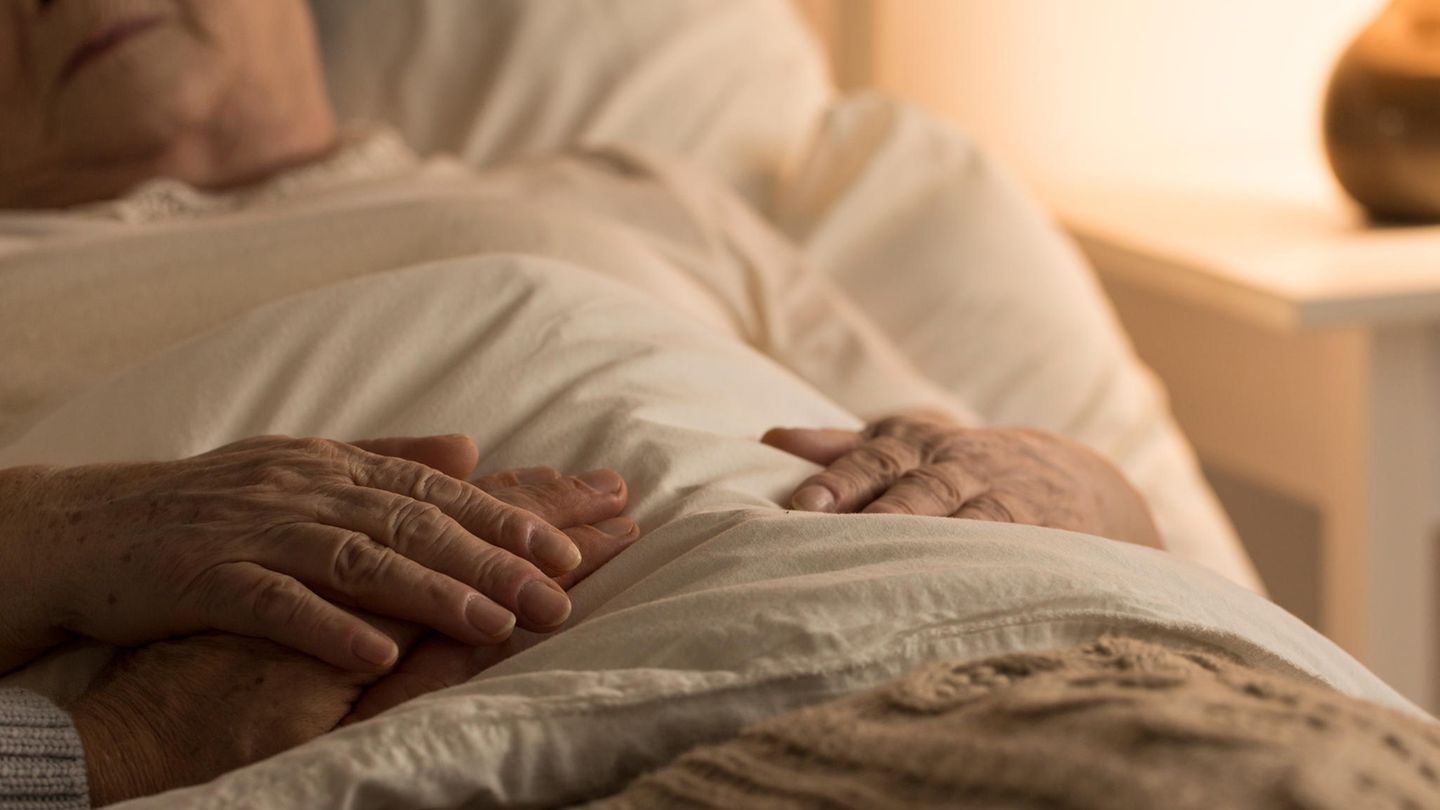Eine Frau liegt im Bett und erhält Beistand
