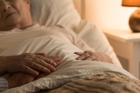 Eine Frau liegt im Bett und erhält Beistand