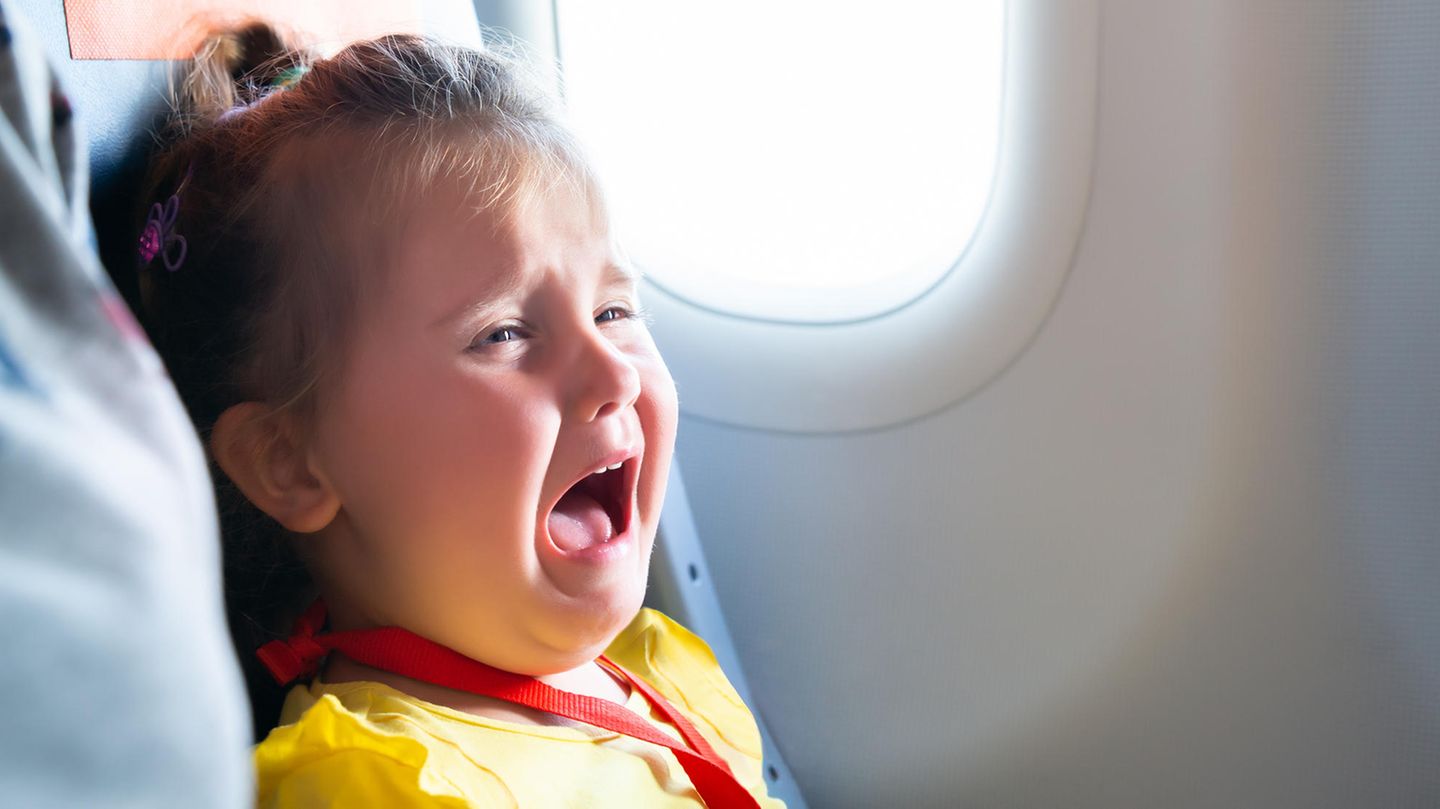 Kleinkind sitzt in einem Flugzeug und schreit