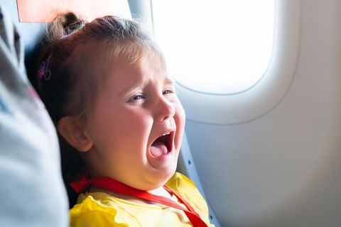 Kleinkind sitzt in einem Flugzeug und schreit