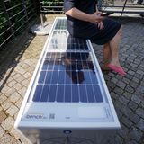 Eine Frau sitzt auf einer Solar-Parkbank in Hamburg