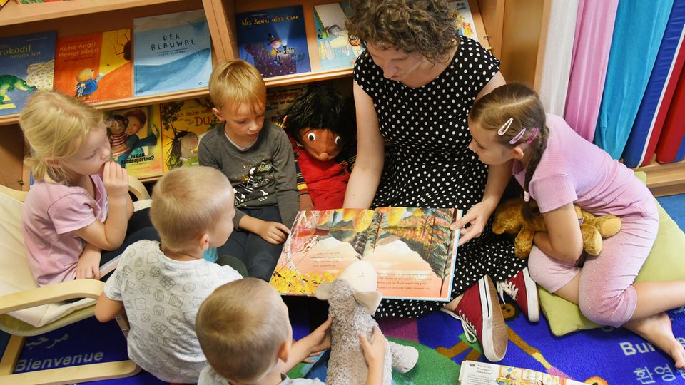 Frau liest Kindern aus Buch vor