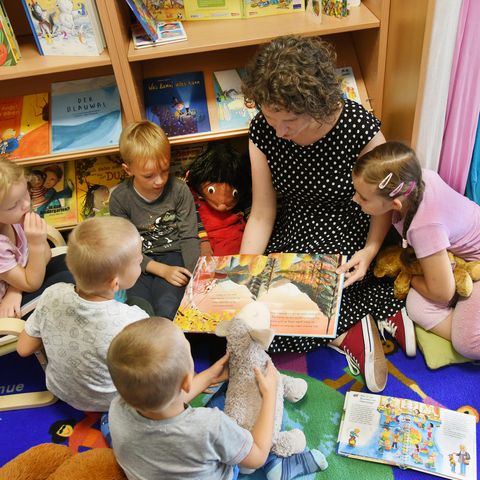 Frau liest Kindern aus Buch vor