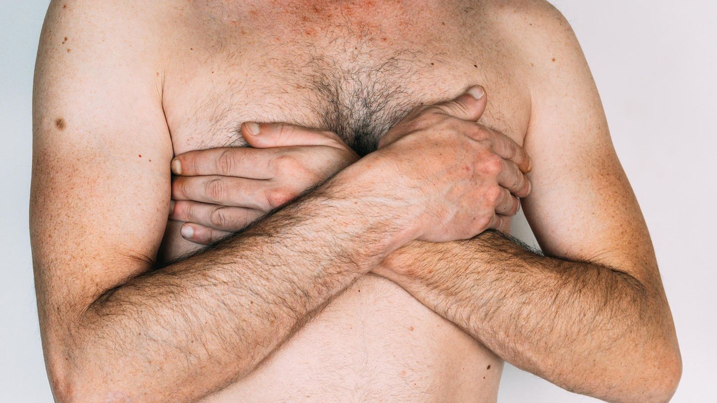 Ein Mann bedeckt seine Brüste mit den Händen