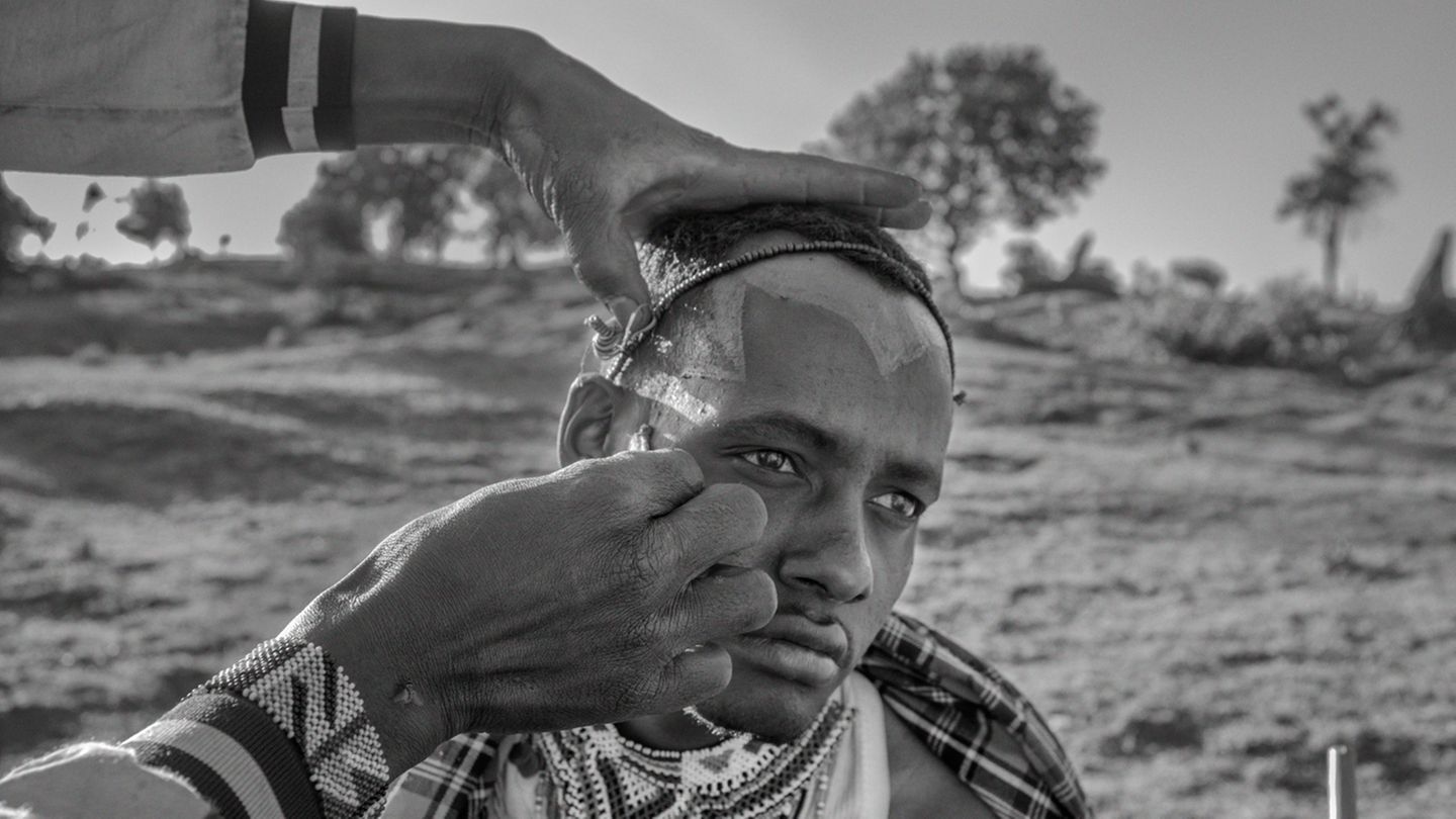 Ein junger Maasai bekommt sein Gesicht bemalt Ein junger Maasai bekommt sein Gesicht bemalt