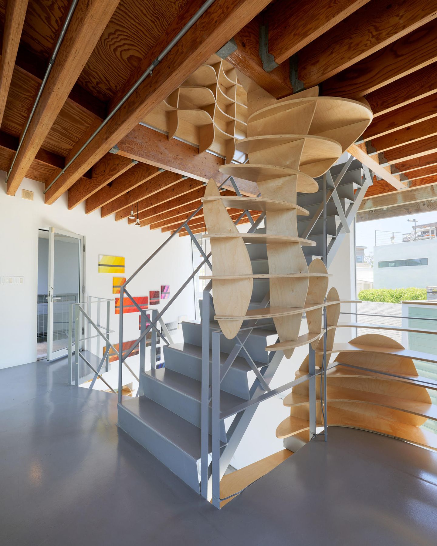 Entlang der Treppe schlängelt sich eine Kunstinstallation aus Holz vom ersten Stockwerk bis in die oberste Etage. Diese dient neben der Optik auch praktischen Zwecken: als Regalfläche und Stauraum in dem nicht gerade einfach zu möblierenden Haus.