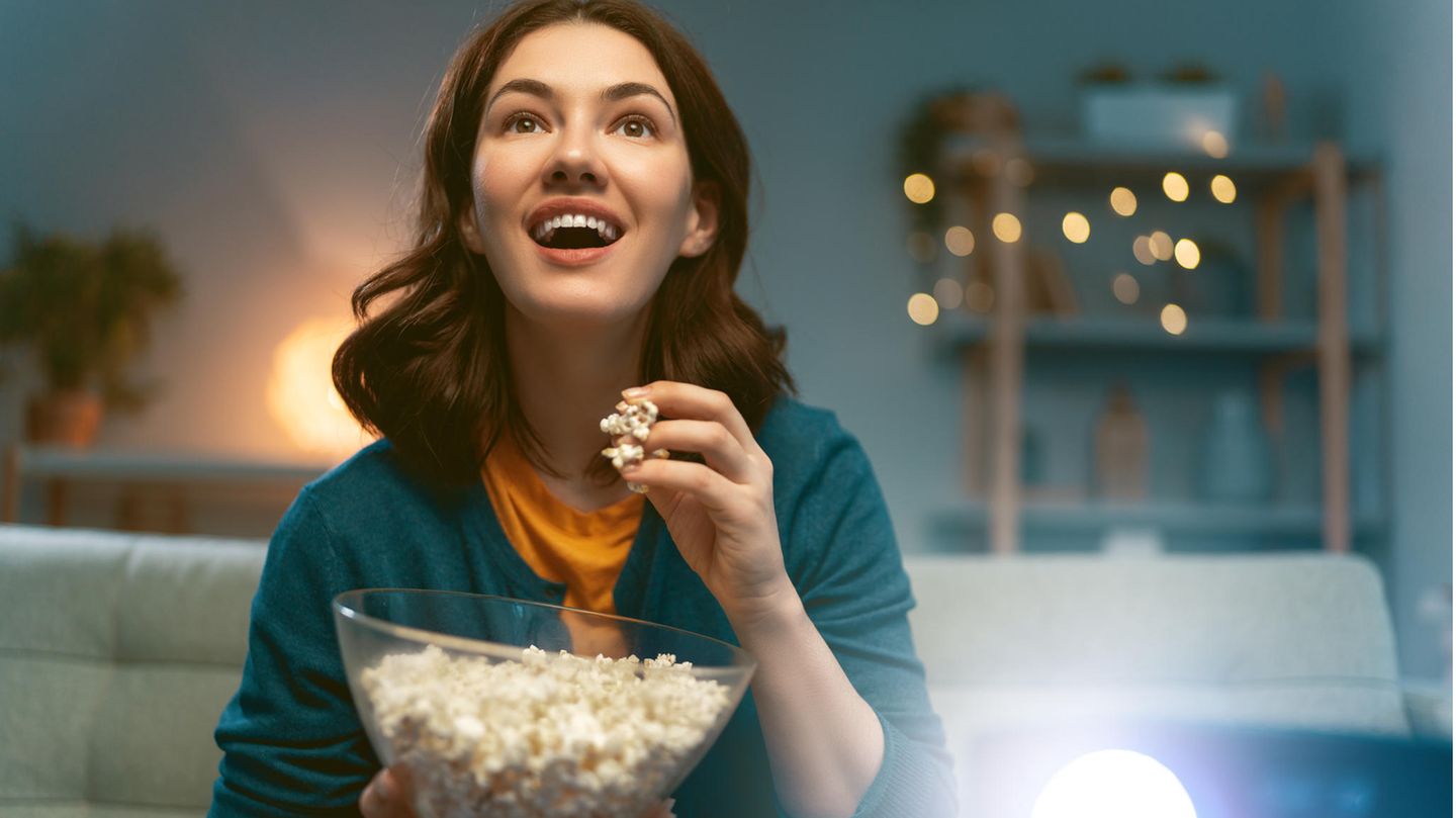 Eine Frau sitzt bei einem Filmabend vor dem Beamer
