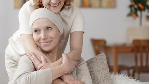 Eine Frau umarmt eine Krebspatientin.