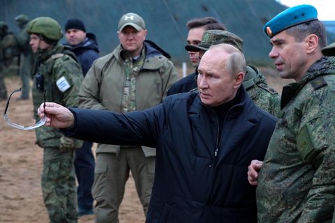 Wladimir Putin zeigt mit einer Brille in der Hand auf etwas beim Besuch eines militärischen Trainingszentrums